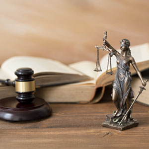 Lady Justice statue with scales, gavel, and open law book, symbolizing criminal defense
